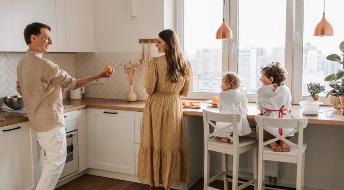 A family having fun preparing breakfast in a cozy kitchen with a city view.